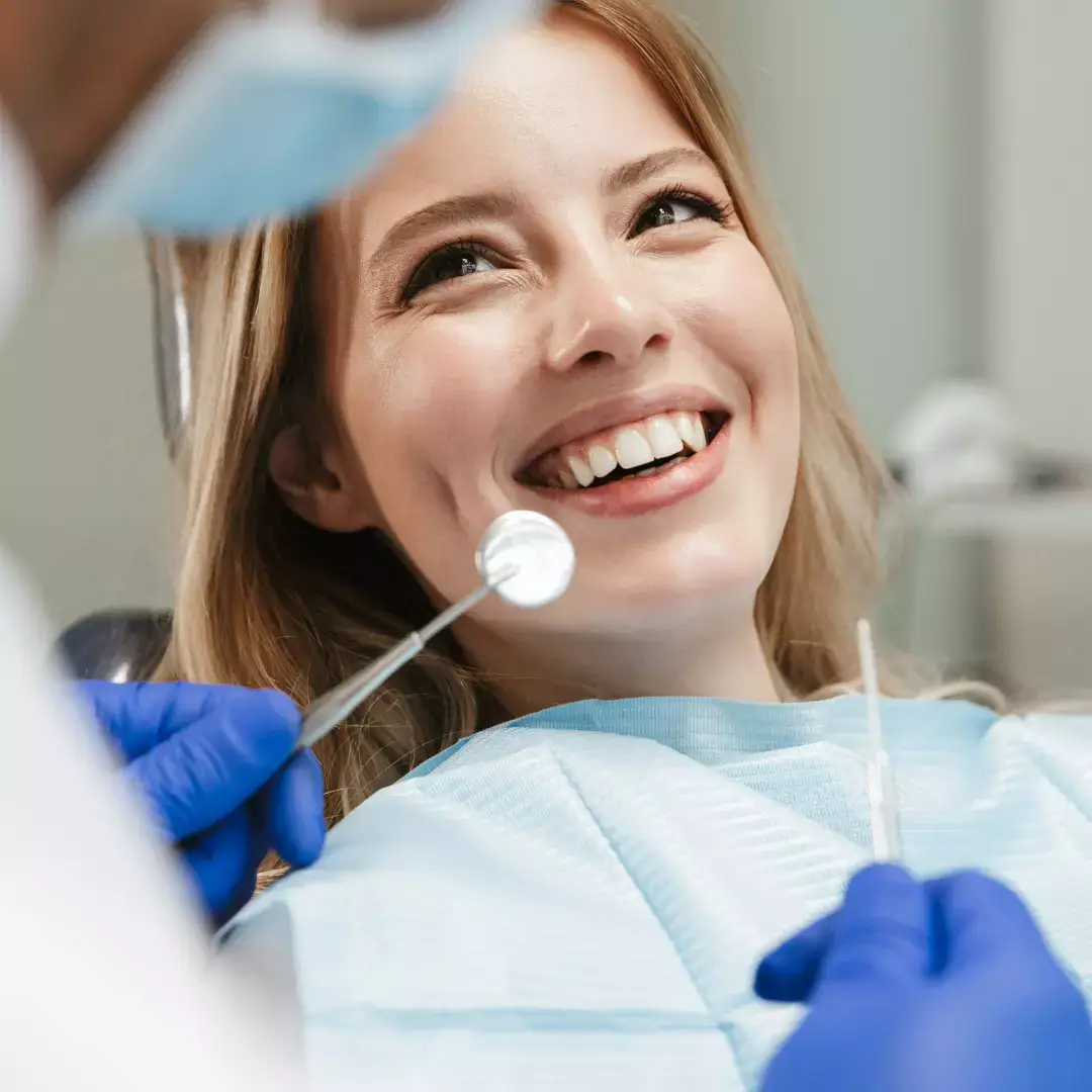 Eine Frau lächelt, während sie in einem Zahnarztstuhl sitzt.