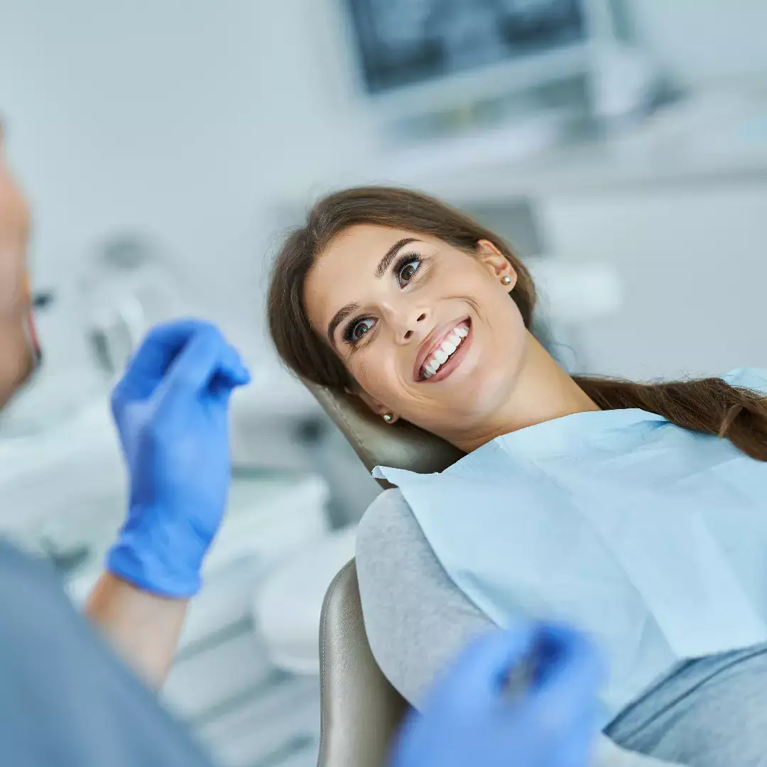 Eine Patientin mit strahlendem Lächeln im Zahnarztstuhl.
